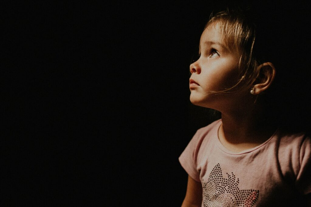 Young child looking up in soft night light, reflecting bedtime wonder and emotional safety