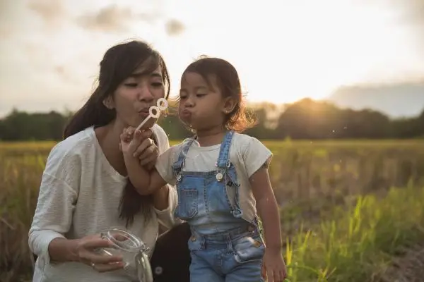 Mother and young child blowing bubbles together, capturing a moment of play and wonder.