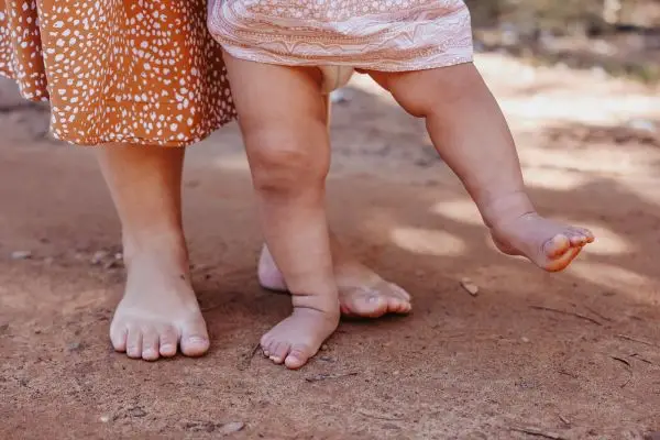 Bare feet of parent and baby walking side by side, symbolizing presence and mindful parenting.